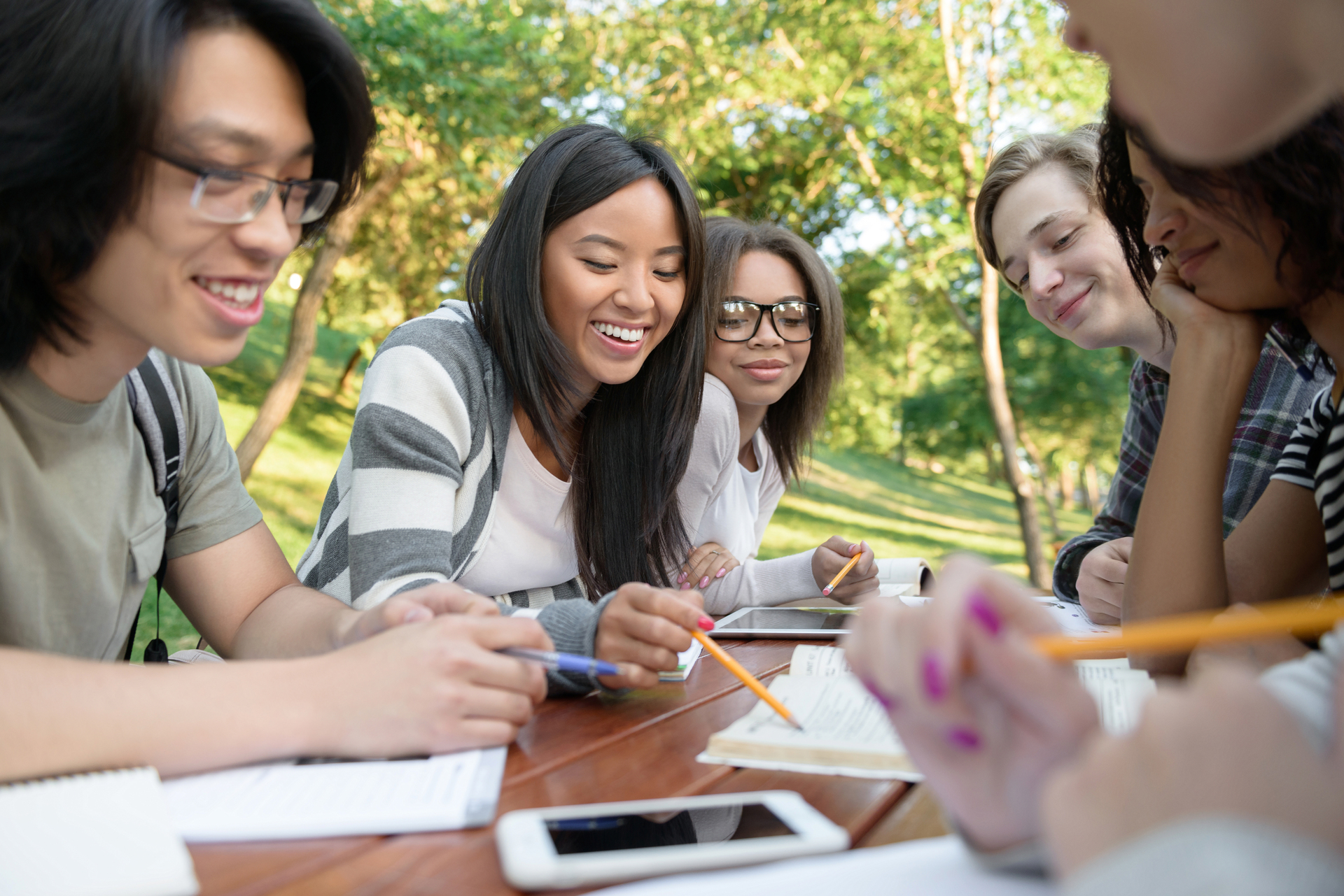 young-students-sitting-studying-outdoors-while-talking